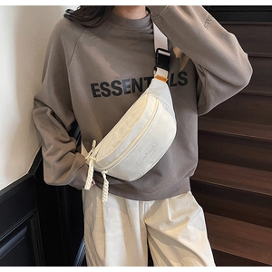 Detail of off-white crossbody chest bag with woven zipper pull and logo engraving