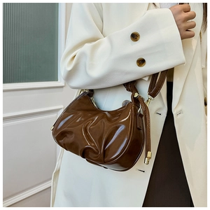 Detail of ruched dark brown glossy leather underarm bag with gold metal zipper