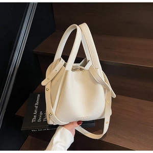 Close-up of off-white lychee grain leather bucket bag with FASHION & BAGS logo detail