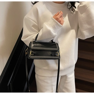 Chic black handbag with pearl detailing shown as a crossbody on a stylish model outfit