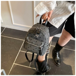 Detail of grey denim texture backpack with black polka dots and silver metal bow accent