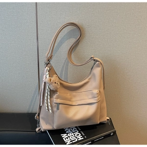 Detail of beige lychee textured hobo bag with zip pocket and cute bear charm pendant