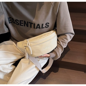Close-up of cream crossbody waist bag featuring woven rope zippers and a round logo