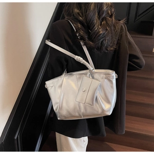 Détail du cabas argenté avec fini métallisé, texture plissée et petit porte-monnaie assorti