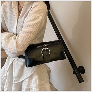 Detail of glossy black patent leather shoulder bag with silver horseshoe buckle decoration
