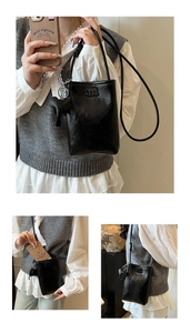 Close-up of black lychee grain leather phone bag with m logo and elephant charm