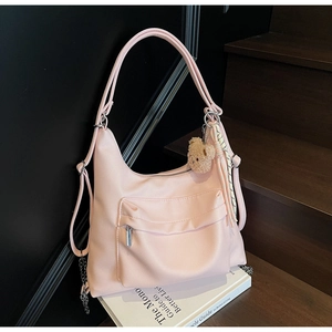 Detail of soft pink leather tote bag featuring a cute bear charm and silk scarf decoration