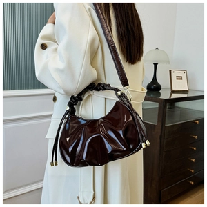 Detail of the pleated texture and glossy oil wax leather on this dark brown handbag