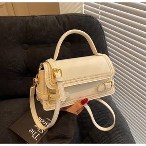 Detail of white PU leather handbag with knitted edge stitching and gold buckle hardware
