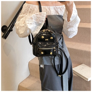 Detailed view of mini black patent leather backpack with golden puppy-style metal rivets