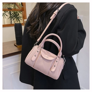 Detailansicht der rosa Boston Tasche mit gewebter Textur und Nieten in einem Café-Ambiente