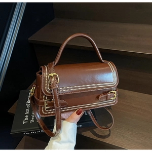 Detailed view of vintage brown leather handbag with pearl edge trim and gold hardware