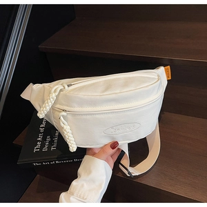 Close-up of minimalist white canvas waist bag featuring embroidered logo and woven zipper tags