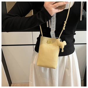 Detail of light yellow crossbody phone bag with elephant charm and M logo