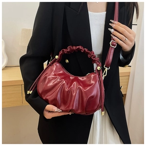 Detailed shot of the burgundy cloud bag with pleated texture and golden hardware