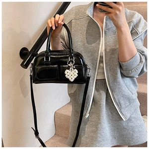 Glossy black Boston bag featuring dual square pockets and a delicate pearl heart charm
