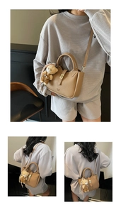 Dettaglio macro della borsa in pelle beige con fibbia dorata e ciondolo a forma di orso