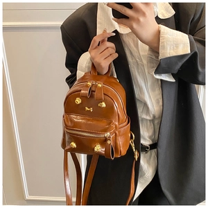 Close-up of brown PU leather backpack with golden animal stud and adjustable strap