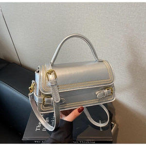 Close-up of silver rectangle handbag featuring yellow stitching and metallic buckle details