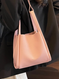 Pink lychee texture bucket bag with minimalist design shown on a model in a black suit