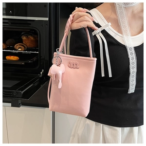 Pink mini phone bag with woven handle and elephant charm held by model in close-up shot