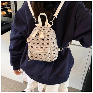 Detail shot of mini beige quilted backpack with black bow pattern on a model