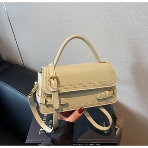 Detail of creamy white leather crossbody bag with gold buckles and scalloped edge stitching