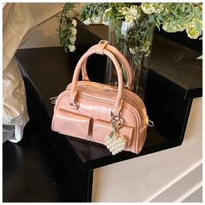 Pink patent leather Boston bag with dual front pockets and pearl heart charm accessory