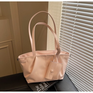 Détail du cabas rose clair en cuir ciré avec mini porte-monnaie et design à plis élégant
