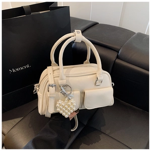 Detail shot of white Boston handbag showing soft PU leather texture and pearl heart charm