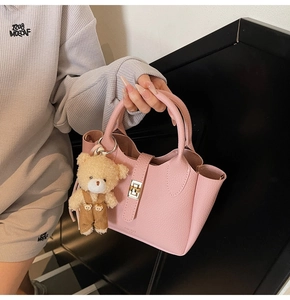 Borsa a secchiello in pelle rosa con chiusura dorata e ciondolo a forma di orso