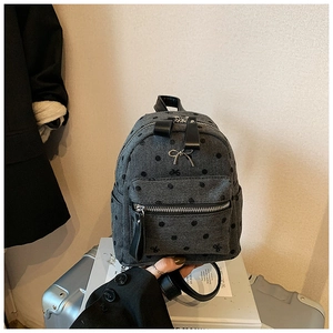 Detail of gray herringbone mini backpack with black polka dots and silver metal bow charm
