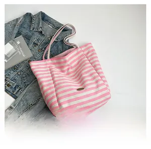 Flat lay of striped canvas tote bag with pink stripes, denim jacket and books