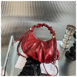 Close-up of ruched wine red oil wax leather cloud bag with metallic industrial backdrop