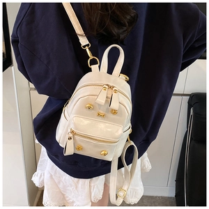 Detail of white leather mini backpack with golden bear rivets and shiny zippers