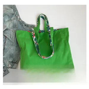 Detail of green canvas tote bag featuring red Our Love text and floral print lining