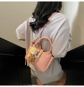 Mini borsa a secchiello in pelle rosa testurizzata con chiusura d'oro e charm a orsetto
