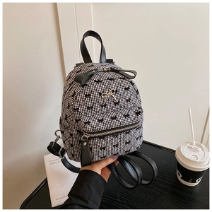 Detail of mini backpack with black and white checkered pattern and small bow decorations