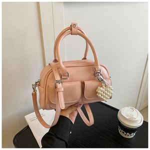 Detail of pink Boston bag with twin pockets, double handles, and pearl heart charm
