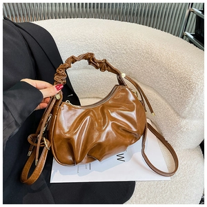 Macro shot of brown pleated dumpling bag showing glossy oil wax leather texture