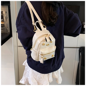 Detailed macro view of a white mini backpack with gold rivets and metallic hardware