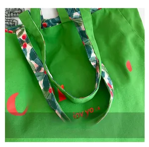 Detail of green canvas tote with red our love lettering and floral pattern handle