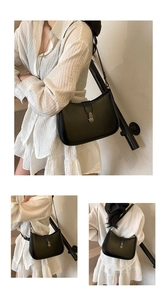 Detail view of a black leather underarm bag featuring a vintage round metal buckle and strap