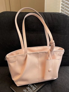 Sac fourre-tout rose en similicuir brillant avec petite pochette sur un siège noir