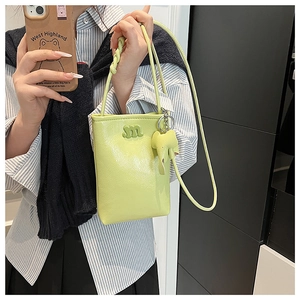Detail of light green litchi grain mini crossbody bag with m applique and elephant charm