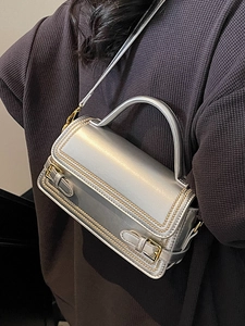 Minimalist silver metallic crossbody bag with gold buckle straps and top handle