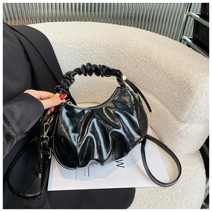 Detail of ruffled handle and glossy oil wax leather texture on a black cloud bag