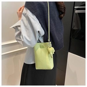 Detail of avocado green crossbody bag with a 3D letter M and a cute elephant pendant
