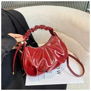 Detail of burgundy glossy cloud bag with pleated texture and adjustable shoulder strap