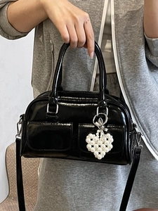 Minimalist black patent leather Boston bag with chic white beaded heart charm and strap